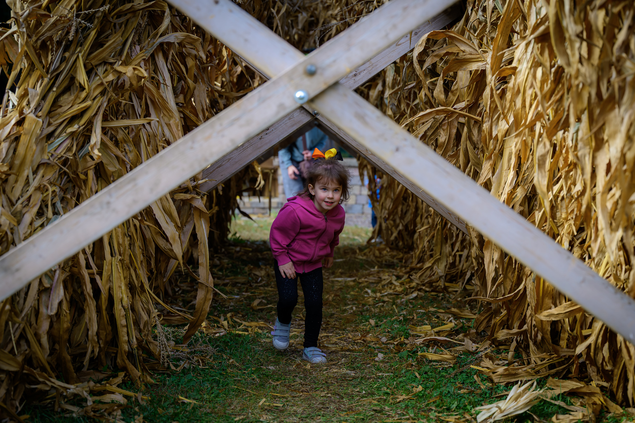 A little girl running through stacks of hay