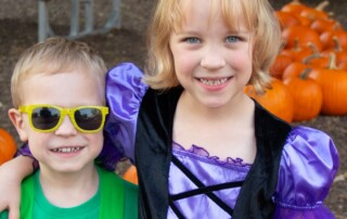 two children in front of pumpkins