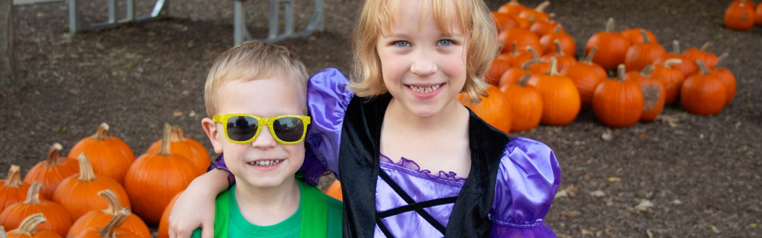two children in front of pumpkins